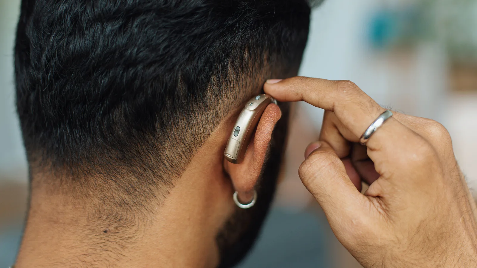 Homem colocando um aparelho auditivo retroauricular